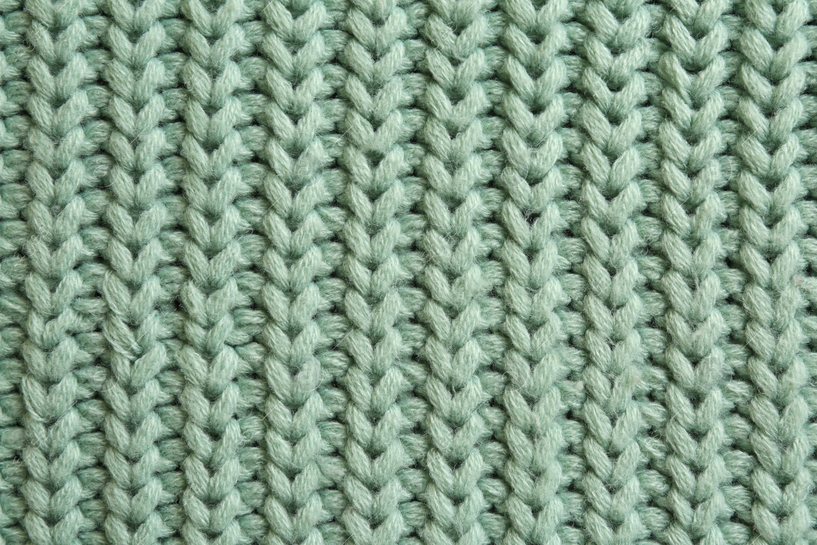 Photo of Beautiful pale green knitted fabric as background, top view