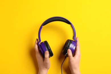 Photo of Woman holding stylish headphones on color background, closeup