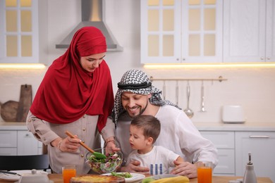 Happy Muslim family eating together in kitchen