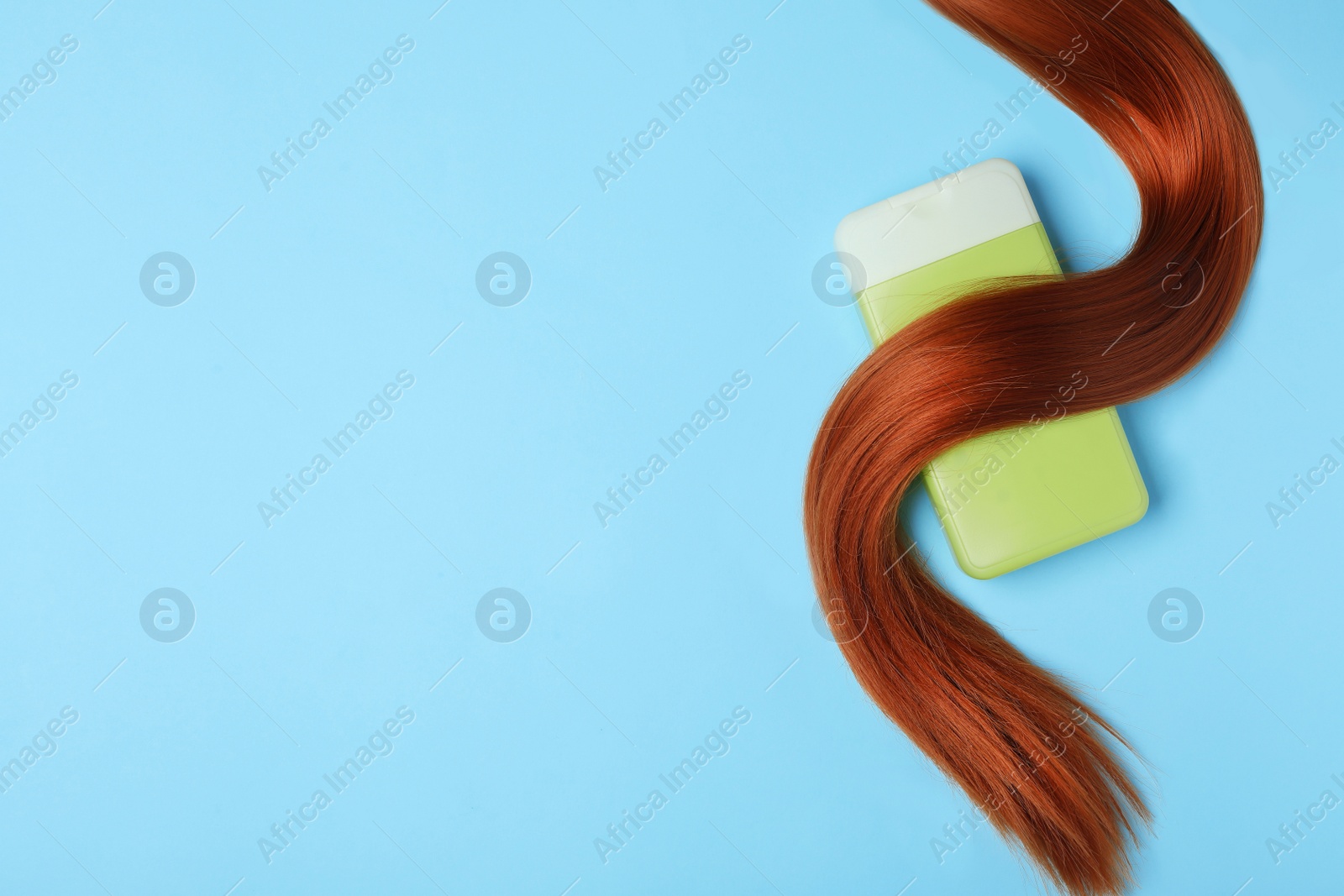 Photo of Bottle of cosmetic product and hair on light blue background, flat lay. Space for text