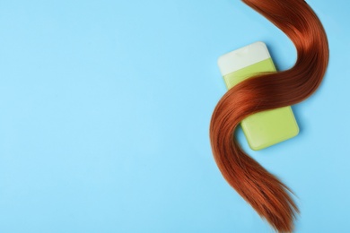 Photo of Bottle of cosmetic product and hair on light blue background, flat lay. Space for text