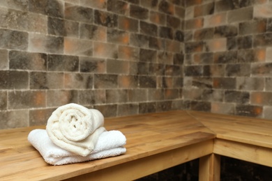 Photo of White towels on wooden bench in salt sauna. Space for text