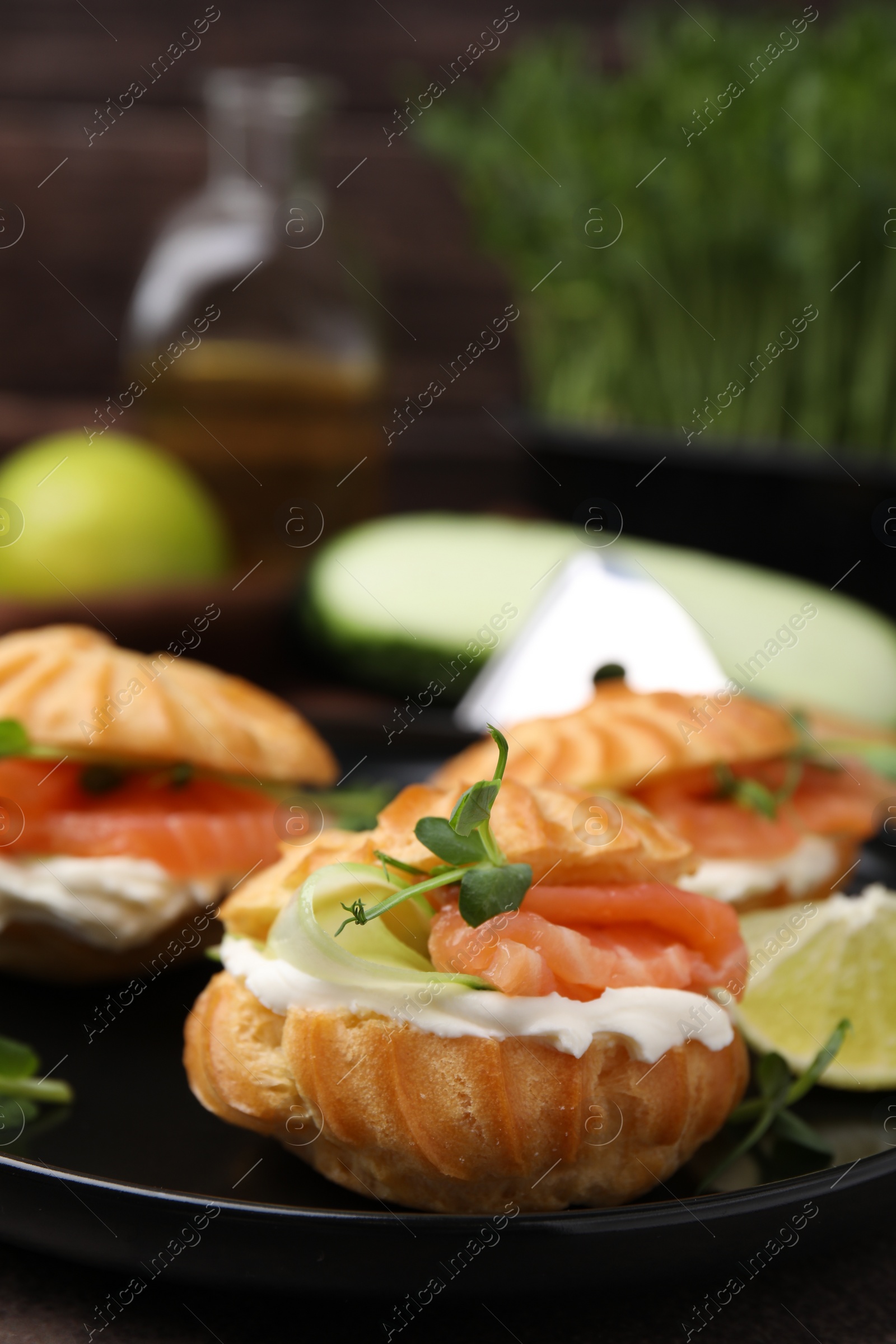 Photo of Delicious profiteroles with cream cheese, salmon and cucumber on plate, closeup