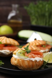 Delicious profiteroles with cream cheese, salmon and cucumber on plate, closeup