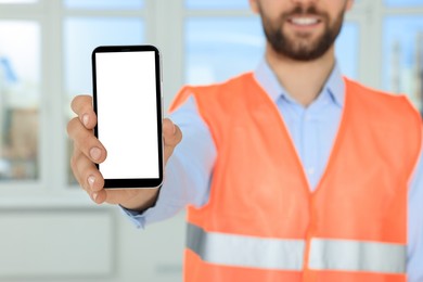 Photo of Man in reflective uniform with phone indoors, closeup
