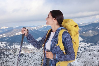 Image of Woman with backpack and trekking poles in snowy mountains