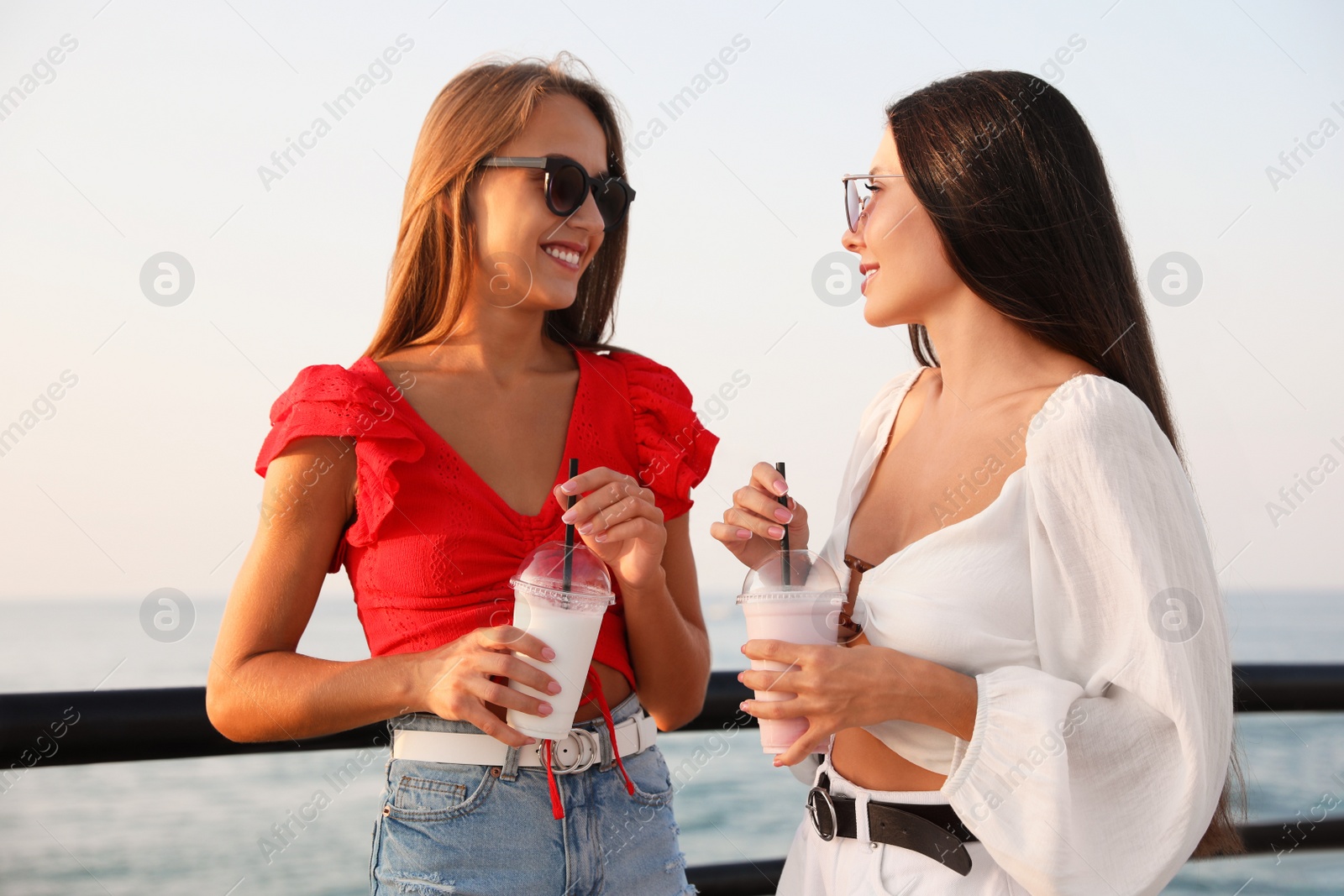 Photo of Beautiful women with tasty milk shakes near sea