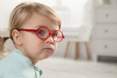 Photo of Cute little girl in glasses at home. Space for text