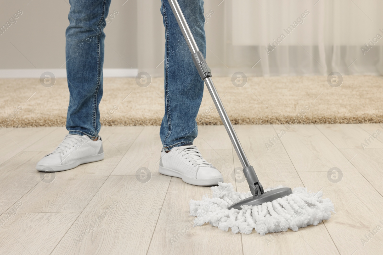 Photo of Man cleaning floor with mop at home, closeup