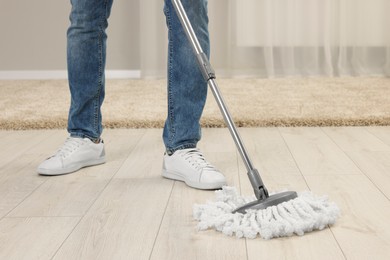 Man cleaning floor with mop at home, closeup