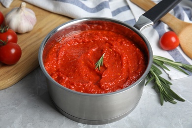 Photo of Delicious tomato sauce in pan on marble table