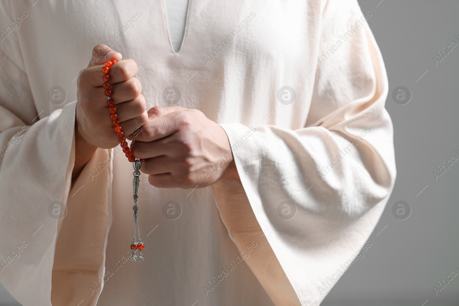 Photo of Muslim man with misbaha on light grey background, closeup