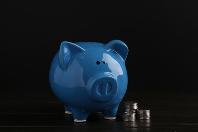 Photo of Financial savings. Piggy bank and coins on wooden table