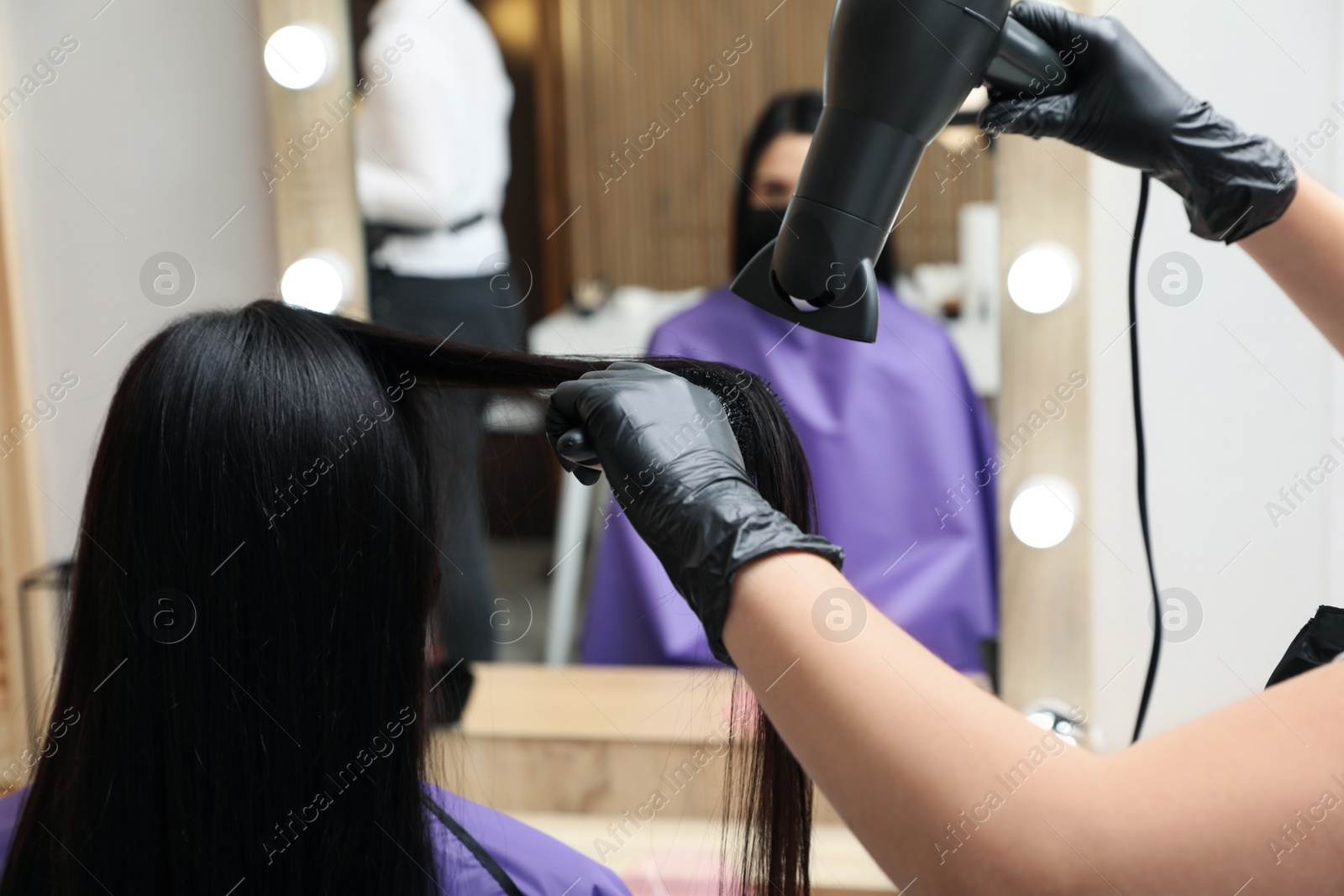 Photo of Professional stylist working with client in beauty salon, closeup. Hairdressing services during Coronavirus quarantine