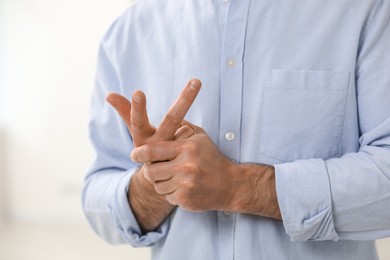 Photo of Man cracking his knuckles on blurred background, closeup. Bad habit