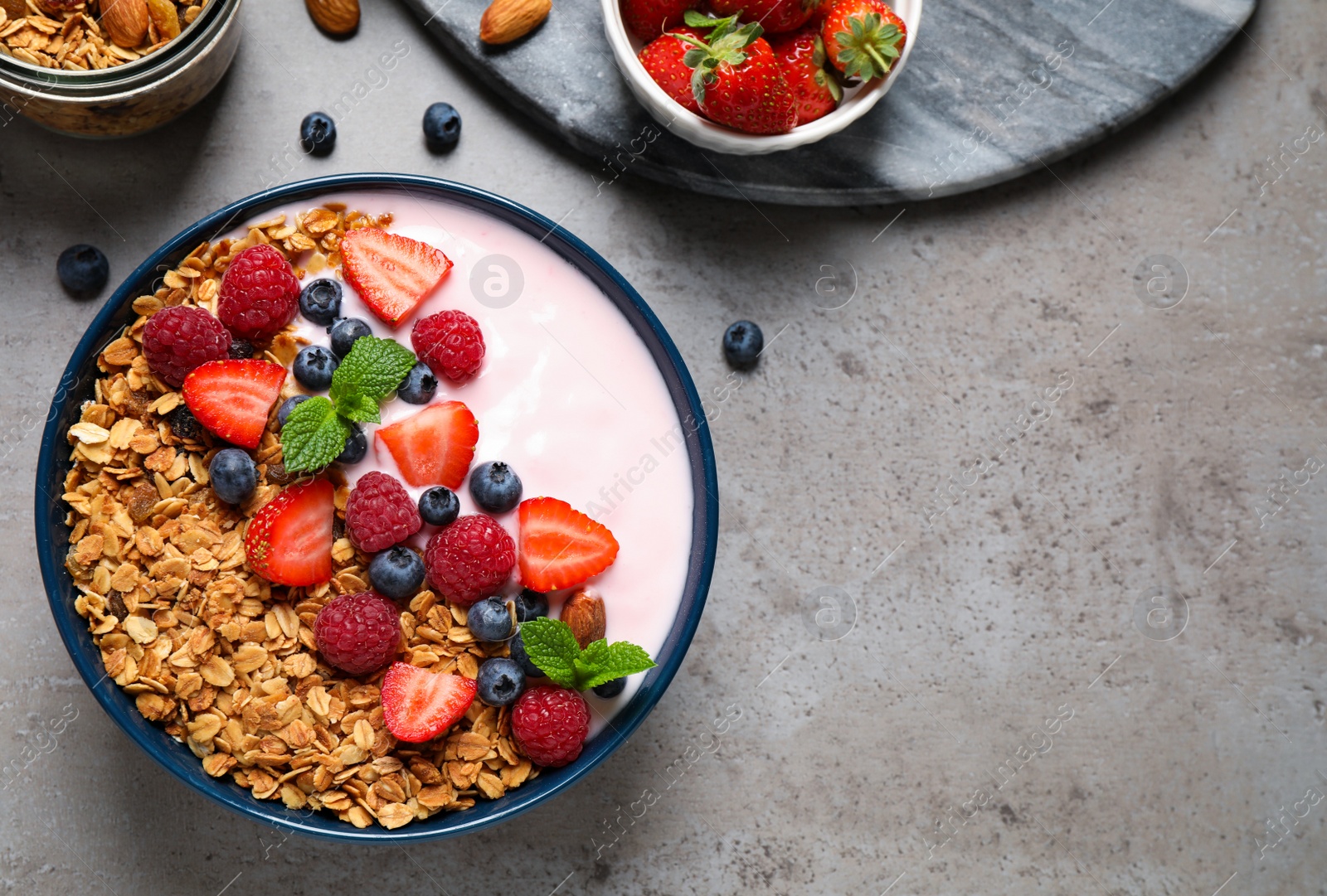 Photo of Healthy homemade granola with yogurt on grey table, flat lay. Space for text