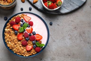 Healthy homemade granola with yogurt on grey table, flat lay. Space for text