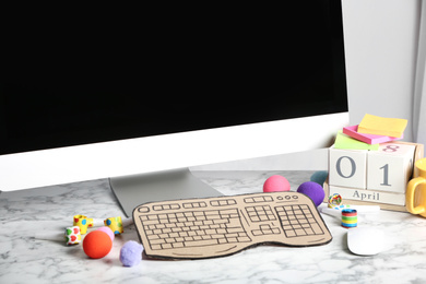 Computer with cardboard keyboard on white marble table. April Fool's Day