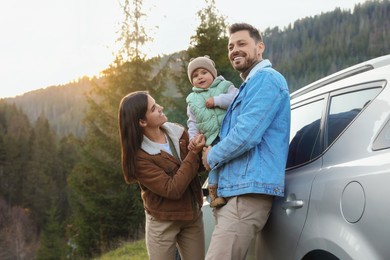 Photo of Parents and their daughter near car in mountains. Family traveling