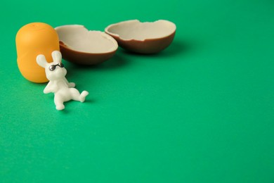 Photo of Slynchev Bryag, Bulgaria - May 25, 2023: Halves of Kinder Surprise Egg, plastic capsule and toy bunny on green background, space for text