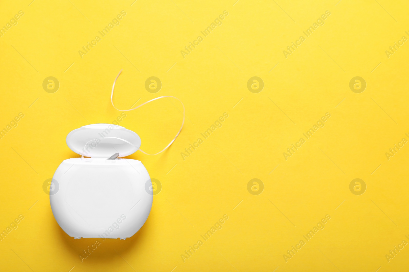 Photo of Container with dental floss on yellow background, top view. Space for text