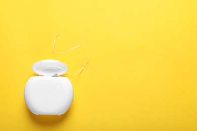 Photo of Container with dental floss on yellow background, top view. Space for text