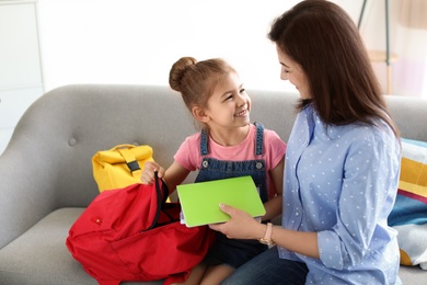 Young woman helping her little child get ready for school at home