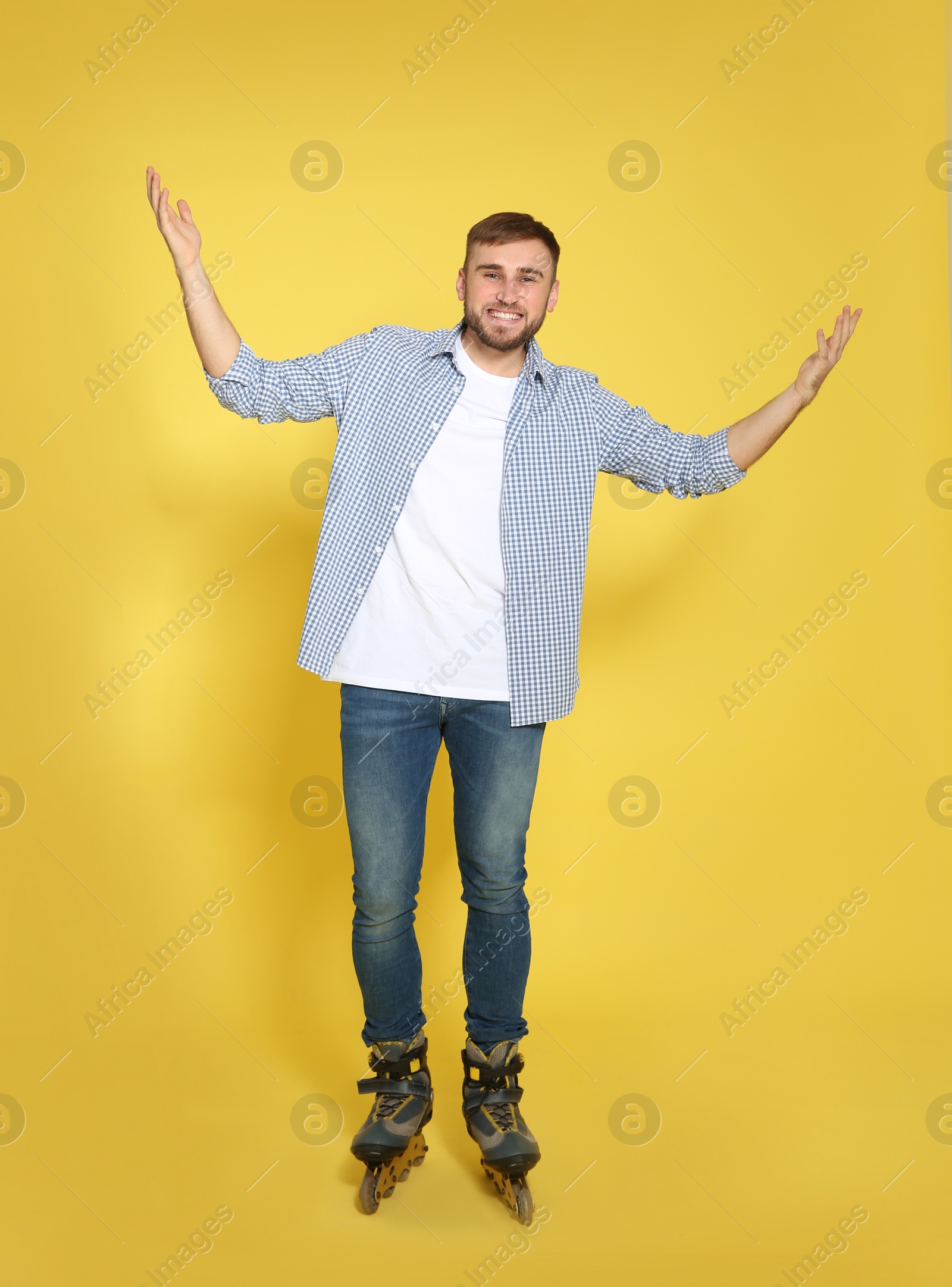 Photo of Full length portrait of young man with inline roller skates on color background