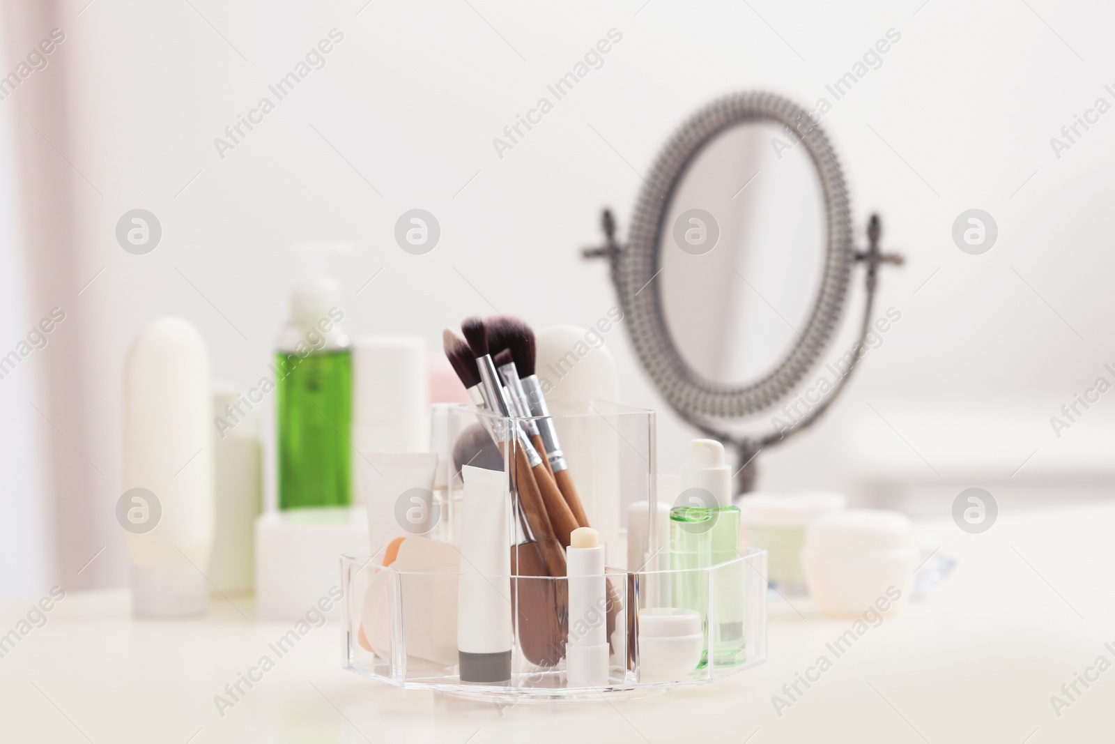 Photo of Organizer with cosmetic products and makeup accessories on table against blurred background