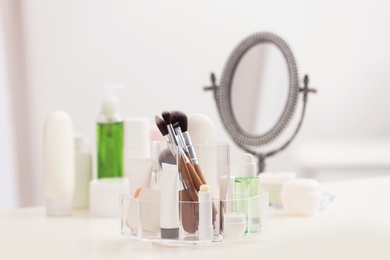 Organizer with cosmetic products and makeup accessories on table against blurred background