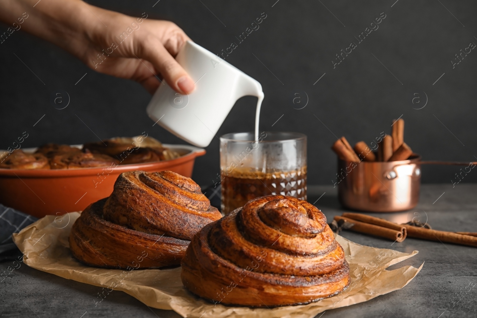 Photo of Parchment with freshly baked cinnamon rolls on table