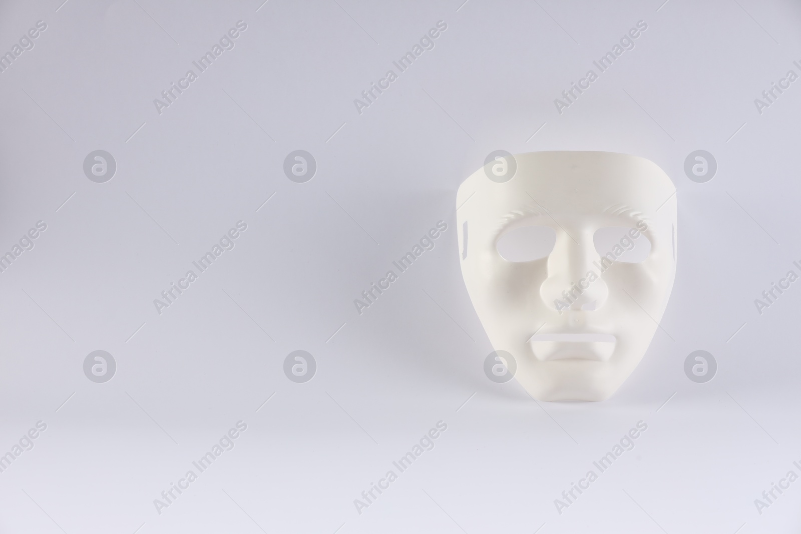 Photo of Plastic face mask on white background, space for text. Theatrical performance