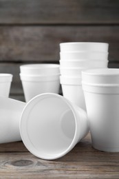 Photo of Many white styrofoam cups on wooden table, closeup