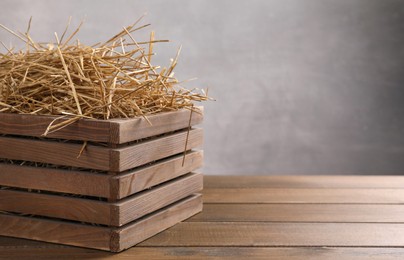 Photo of Dried straw in crate on wooden table, space for text