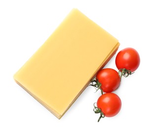 Photo of Stack of uncooked lasagna sheets and tomatoes isolated on white, top view