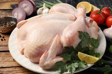 Photo of Fresh raw chicken with different products on wooden table