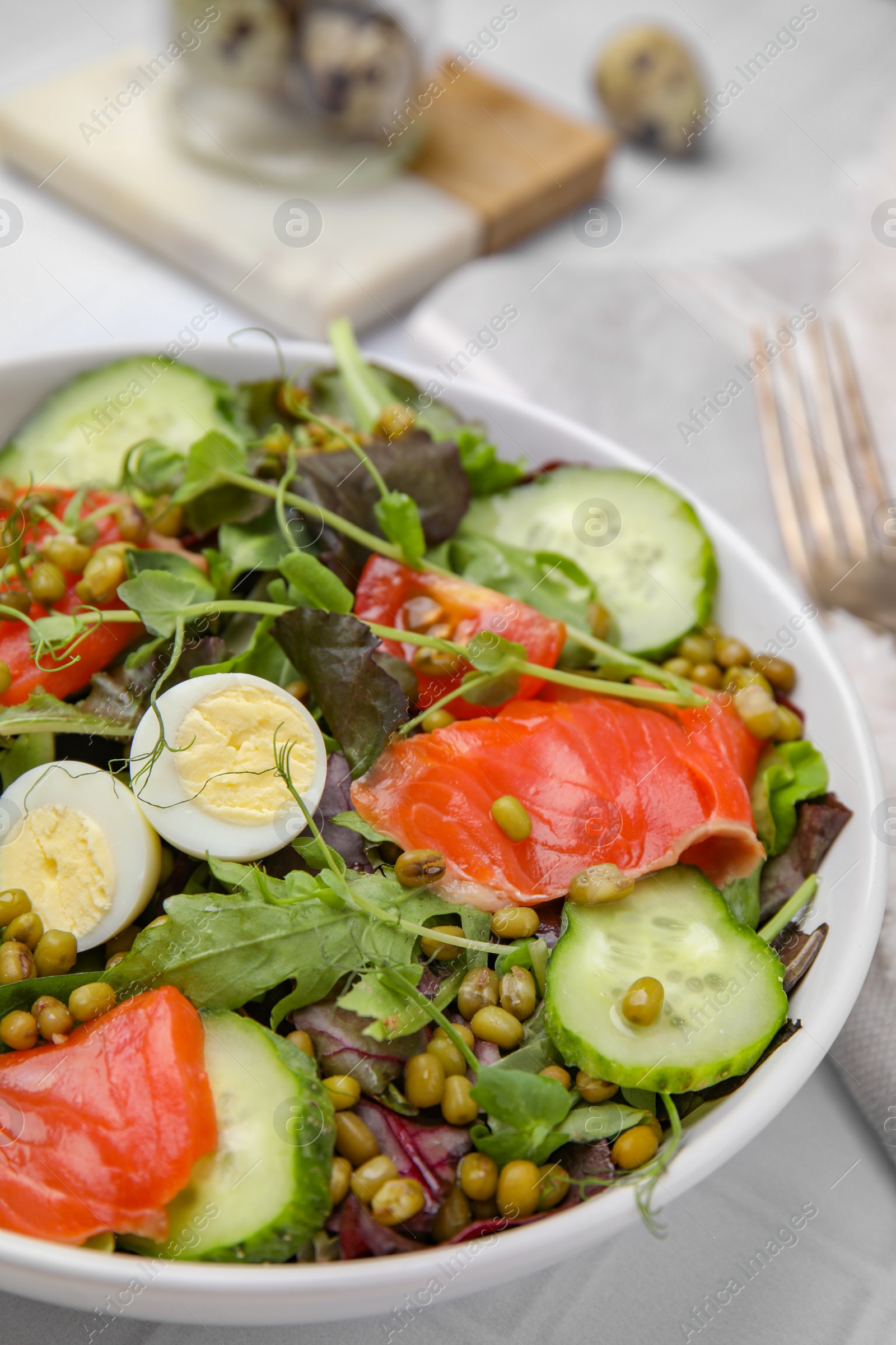 Photo of Bowl of salad with mung beans on white tiled table, closeup