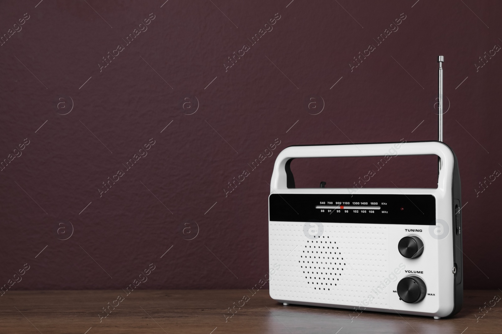 Photo of Retro radio receiver on wooden table against brown background. Space for text