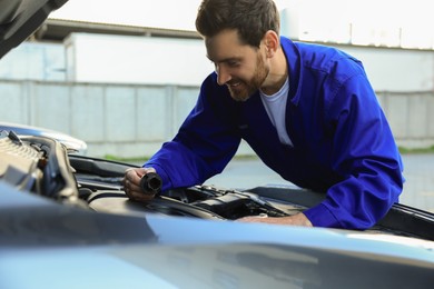 Photo of Worker working with modern car engine outdoors