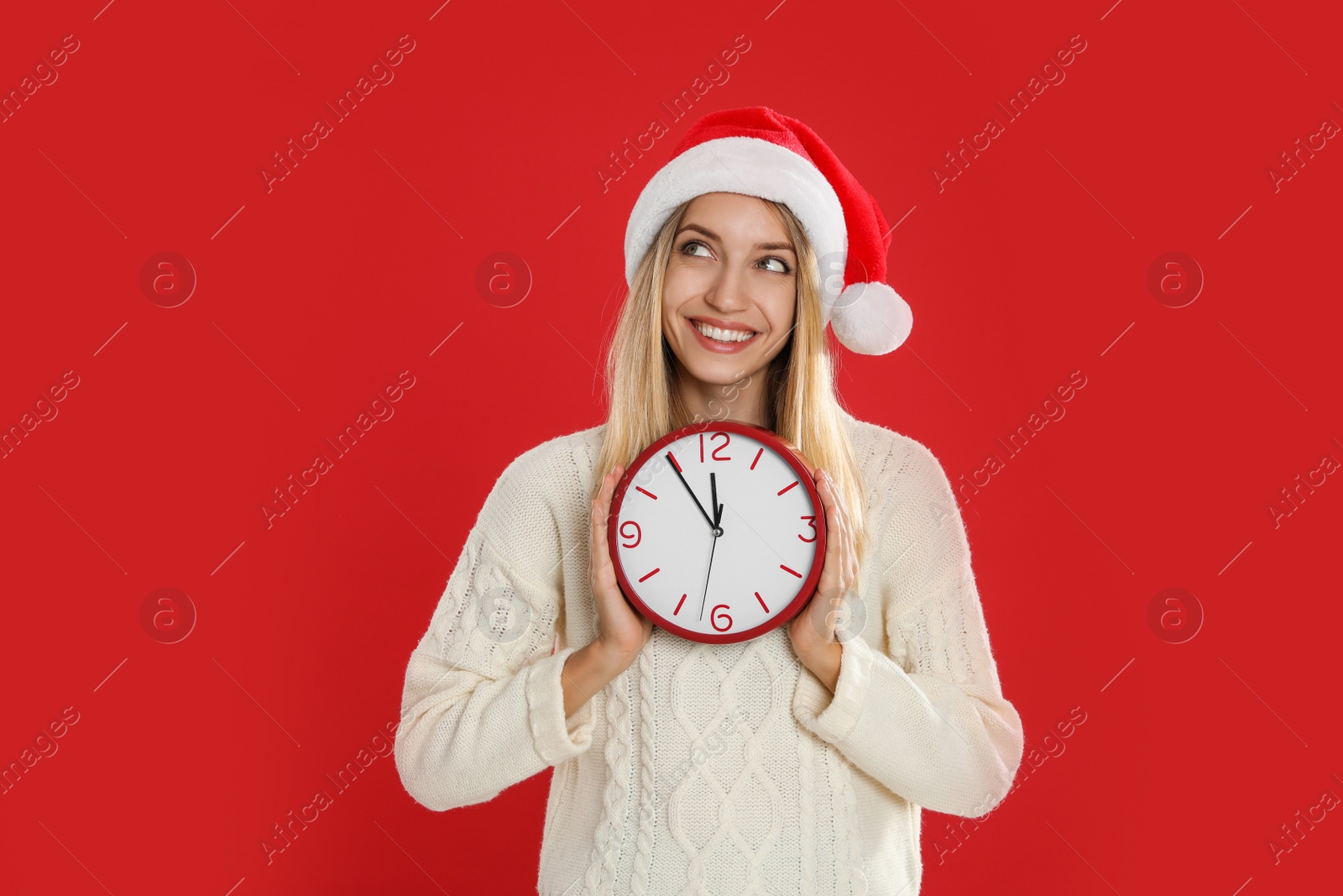 Photo of Woman in Santa hat with clock on red background. New Year countdown