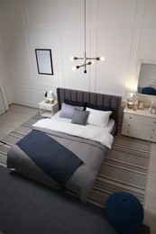 Photo of Stylish bedroom interior with large comfortable bed and chest of drawers, above view