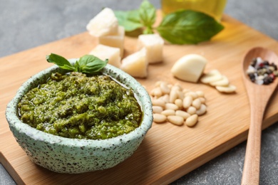 Photo of Board with bowl of pesto sauce on table, closeup. Space for text