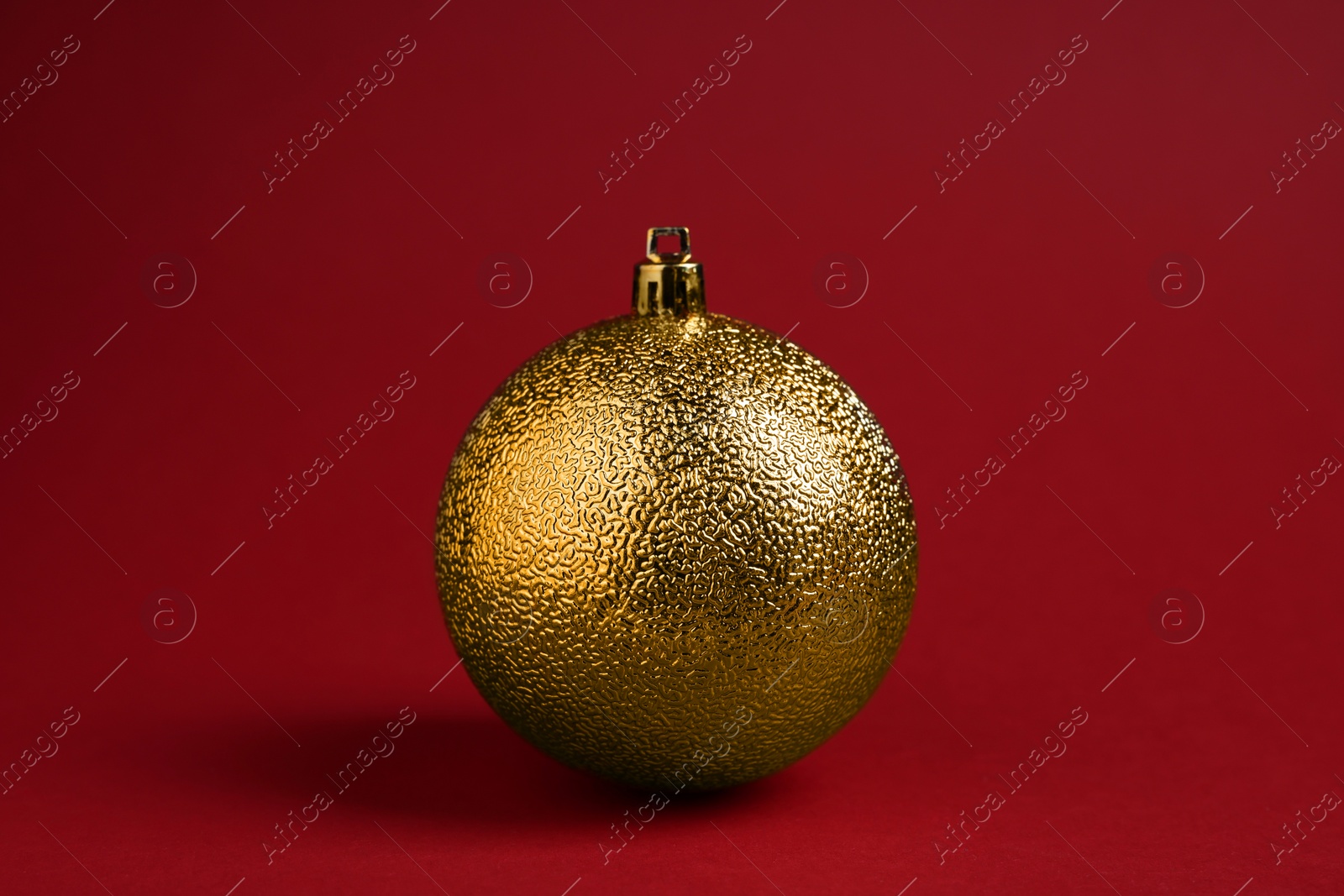 Photo of One golden Christmas ball on red background