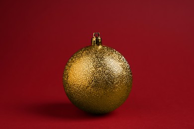 One golden Christmas ball on red background