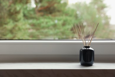Aromatic reed air freshener on windowsill indoors, space for text