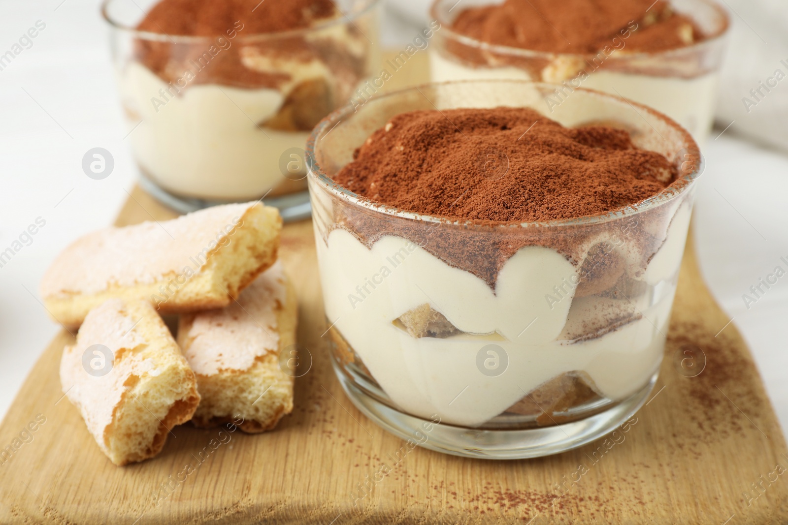 Photo of Delicious tiramisu in glasses and cookies on table, closeup