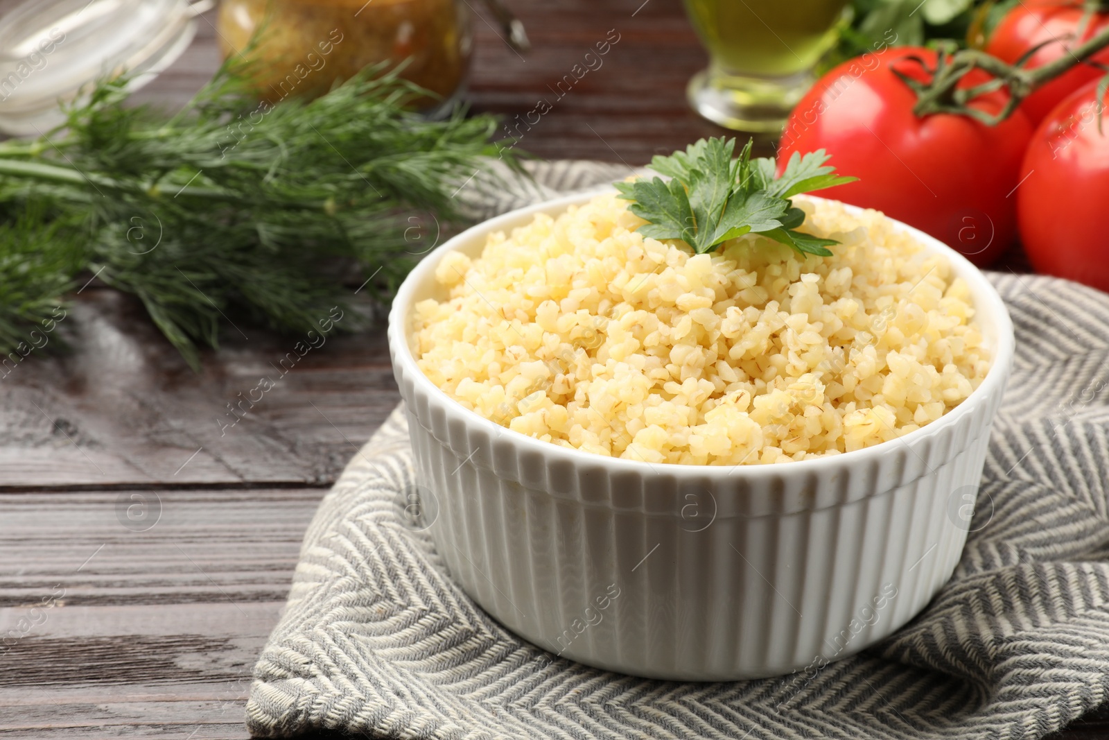 Photo of Delicious bulgur with parsley in bowl on wooden table, closeup