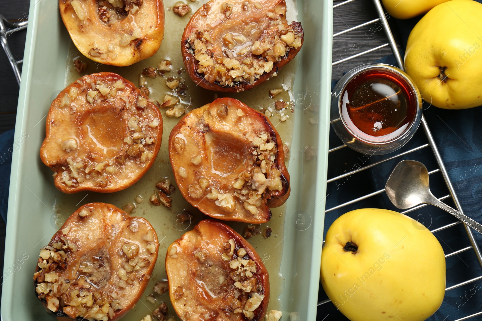 Photo of Tasty baked quinces with nuts and honey in dish on table, flat lay