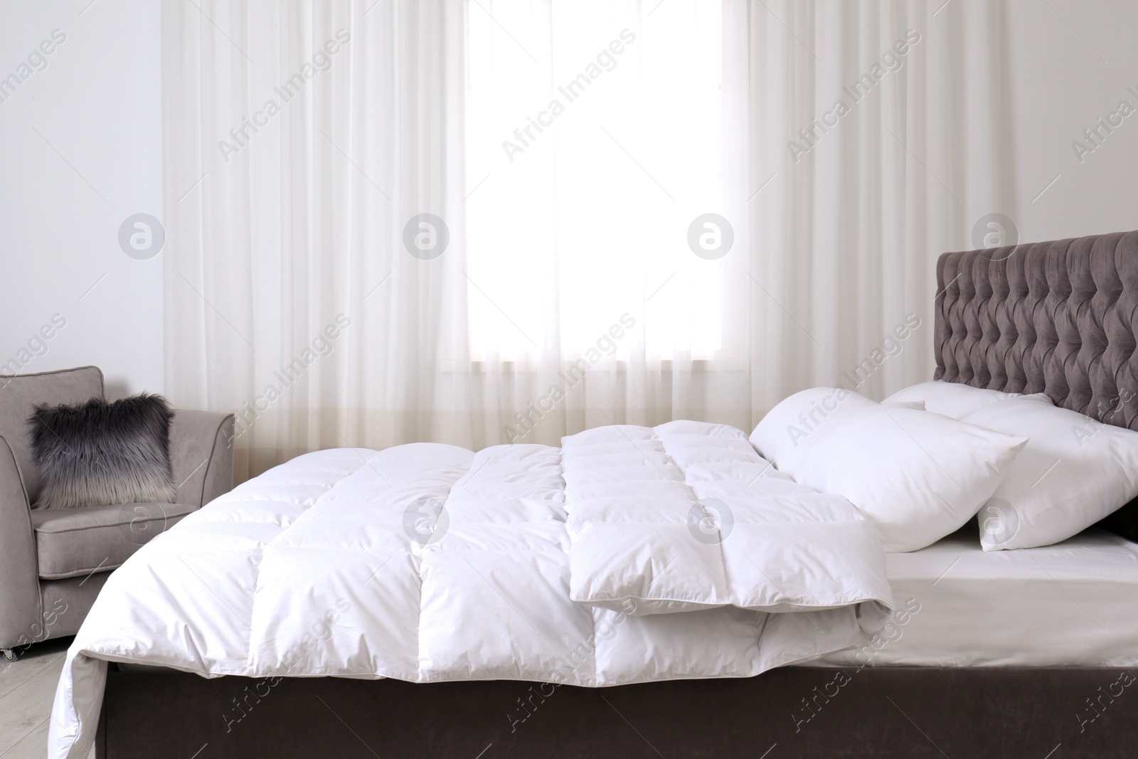 Photo of Large comfortable bed in light room. Stylish interior