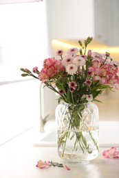 Photo of Vase with beautiful flowers on kitchen counter. Stylish element of interior design